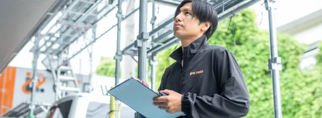 住宅の外壁を確認し、外壁塗装や外壁洗浄を提案するスタッフ