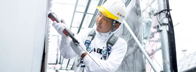 外壁塗装前のシーリング施工を行う職人が丁寧に補修している様子