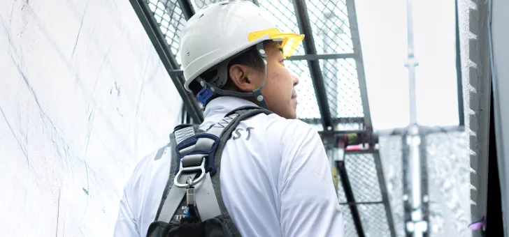 外壁塗装を行う職人が足場の上から建物の状態を確認している様子