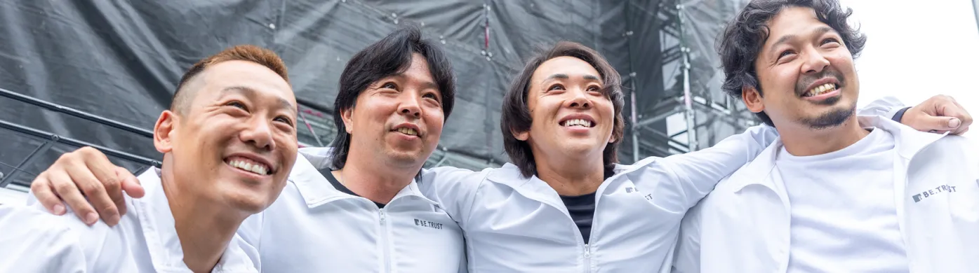 BE.TRUSTのスタッフが笑顔で肩を組み並ぶ集合写真