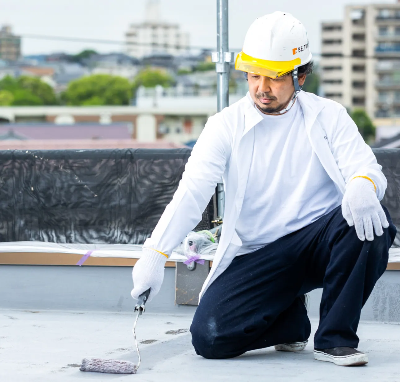 屋上防水工事を行う職人が防水材を施工している様子