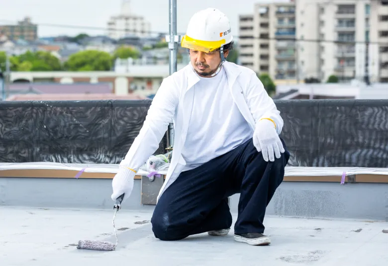 屋上防水工事を行う職人が防水材を施工している様子
